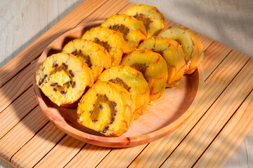 Slice of vanilla roll with pineapple jam filling on wooden plate