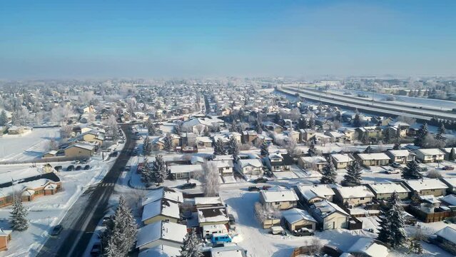 Drone footage of Airdrie Alberta, small suburban city, covered in snow and hoar frost. Blue cloudless sky, 