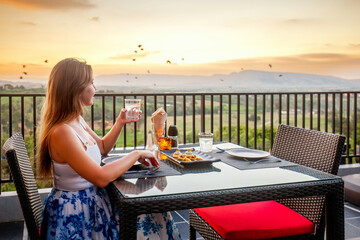 Fototapeta na wymiar Dinner with sunset mountain view. Elegant woman in luxury outdoor restaurant. Leisure, holidays, travel concept.