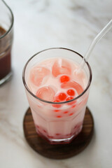 A glass of strawberry milk bubble tea with tapioca pearls on the table. Milky drink with tapioka...