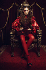 Woman dressed as the queen of hearts, creative make up with big heart on eye, girl sitting in the...