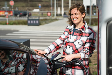 Woman in a plaid shirt charging an electric car	