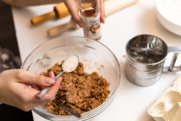 The process of quenching the vinegar in a teaspoon over the dough. The process of making cookies at home.