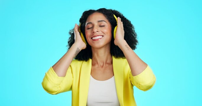 Music headphones, dance and woman in studio isolated on a blue background. Technology, finger snap and happy female dancing, streaming or listening, enjoying podcast or radio sound, audio or album.