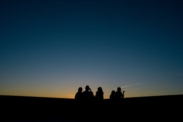 
silhouettes of people watching the sunset in a town in spain