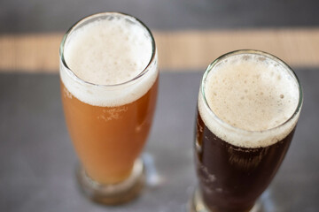 dos pintas de cerveza artesanal en vaso trago largo sobre barra dorada y roja con espuma