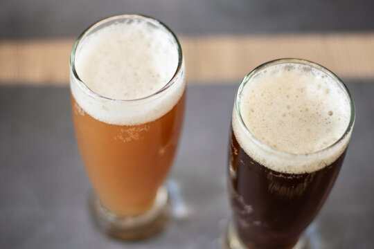 dos pintas de cerveza artesanal en vaso trago largo sobre barra dorada y roja con espuma