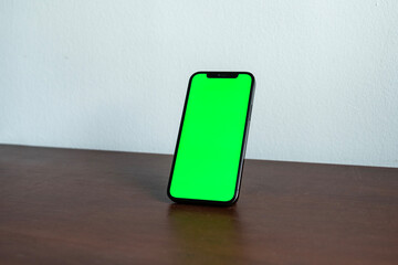 Smartphone on a wooden table with green screen template for social media, web or app mock up