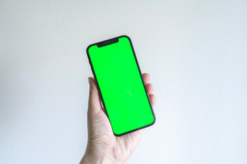 Hand holding a smartphone with green screen template for social media, web or app mock up