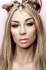 Young attractive cute girl with an unusual creative make-up of wild deer. Halloween ideas of beauty photography