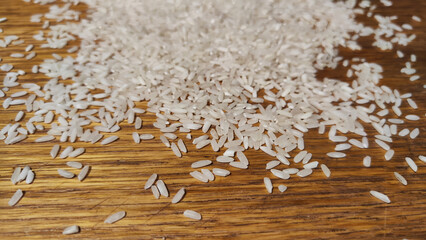 White cereals rice on a brown wooden surface for background and texture. Product and food stored for a long time. Partial focus. Partial focus