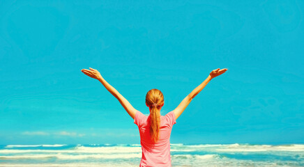 Happy young woman rising her hands up on the beach on sea