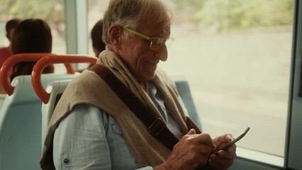 Happy senior man using mobile smartphone while traveling with bus