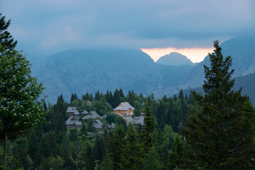 Dramatic storm clouds rolling around mighty mountain peaks above alpine village