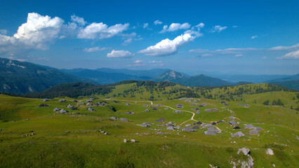 Fototapeta na wymiar AERIAL: Breath-taking view of authentic settlement in beautiful alpine landscape