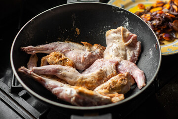 Raw rabbit with spices in a pan. Cooking stewed rabbit.
