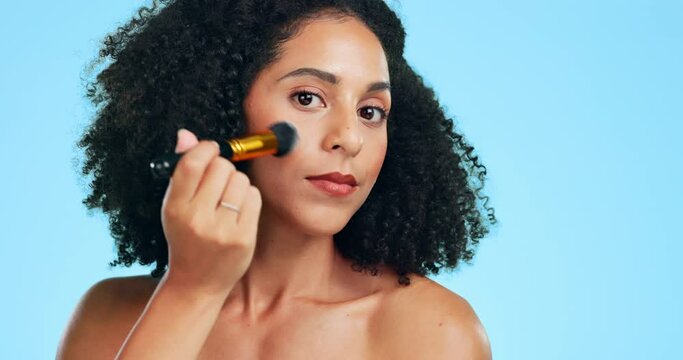 Makeup, serious and portrait of woman apply foundation or contour using brush isolated against a studio blue background. Skincare, self care and female model with cosmetic facial product for beauty