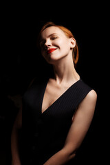 Fototapeta premium Middle age woman smiling on black background. A sophisticated woman of forty years old in black clothes with open arms. Happy face, optimism.