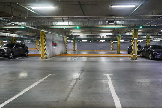 Lines for parking cars. Traffic background, a picture of a parking lot in a shopping center. Underground parking with parked cars, where there is a place to copy. High quality photo