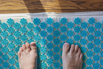 person stands on massage applicator, acupuncture massage mat for meditation and spiritual practices. taking care of yourself is healthy lifestyle. energy and joy. stretching and gymnastics