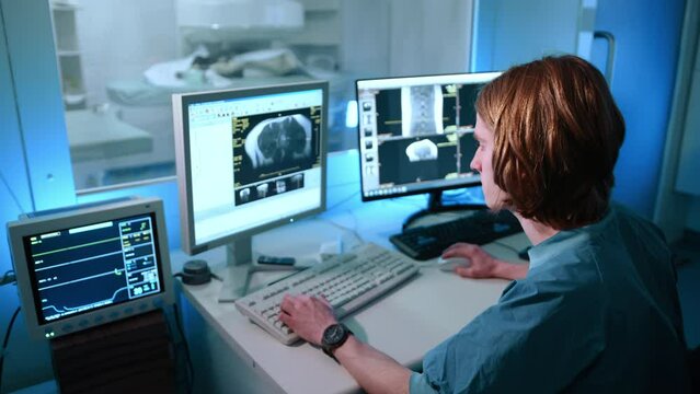A behind view of veterinarian looking at the magnetic resonance image. He looks focused on his work. He is writing something down. High quality 4k footage