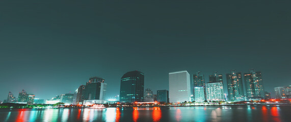 Night view of skyscrapers with river in business district of the capital city in Bangkok, Thailand. with copy space and text design for business