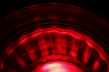 Vaso de cristal transparente con luz rojo con el borde ondulado desenfocado en semicìrculo, forma...