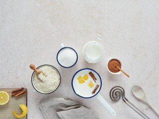 Milk with cinnamon and lemon in a saucepan and ingredients to prepare rice pudding recipe.