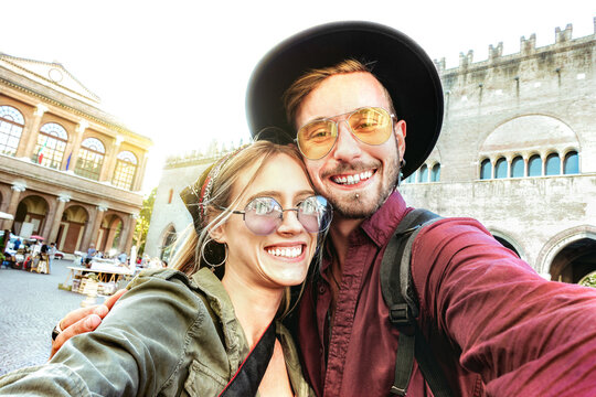 Young man and woman in love having fun taking selfie at old town tour - Wanderlust life style travel concept with lovely tourist couple on city sightseeing vacation - Bright warm sunshine filter
