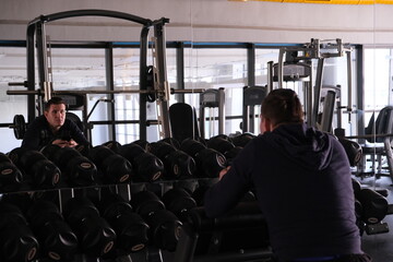 Sports equipment in the gym. Man in Stylish sports space. Expanders and simulators with heavy dumbbells.
Bench press, anaerobic and aerobic exercises.
