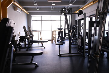 Fototapeta premium Sports equipment in the gym. Stylish bright sports space. Expanders and simulators with heavy dumbbells. Bench press, sport for a strong body and weight loss
