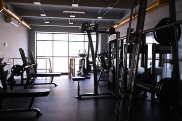Fototapeta na wymiar Sports equipment in the gym. Stylish bright sports space. Expanders and simulators with heavy dumbbells. Bench press, sport for a strong body and weight loss