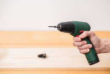 electric screwdriver in a man's hand on a white background, as well as on a tree background