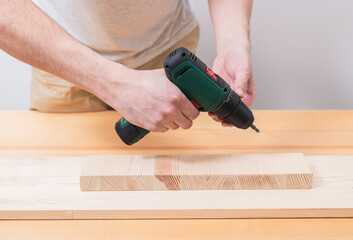 A man works with an electric screwdriver on a wooden table