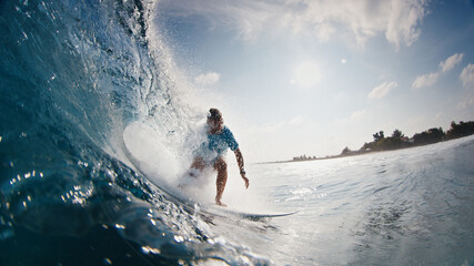 Surfer rides the wave. Young man surfs the ocean wave in the Maldives and tries to get barrelled