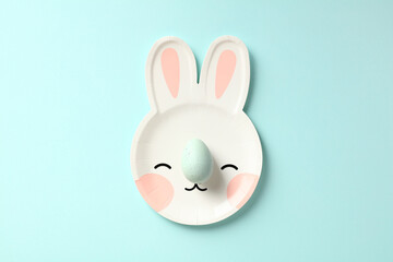 Easter bunny shaped plate with Easter egg on blue table. Minimal style.