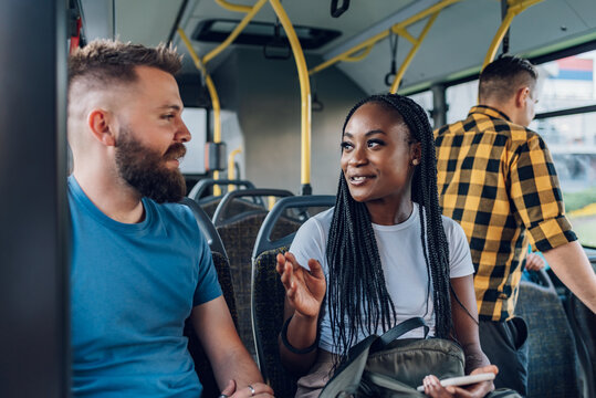Multiracial friends talking while riding a bus in the city