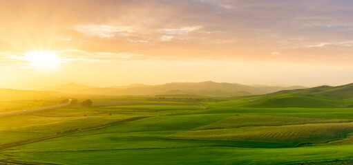 Obraz premium countryside sunset in green hills of spring fields with old castle farm and mountains on background of evening landscape