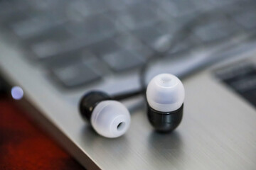 Black earphone, close up photo, on the laptop keyboard