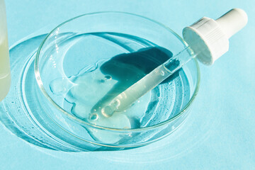 Petri dish. With transparent gel. The pipette lies. Cosmetic dispenser. On a blue background.