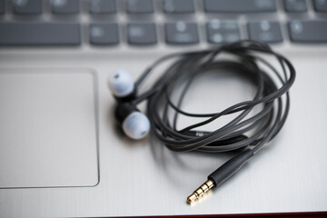 Black earphone, close up photo, on the laptop keyboard