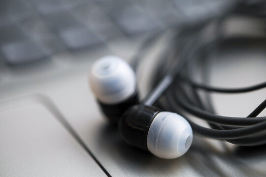 Black earphone, close up photo, on the laptop keyboard