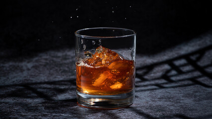 Whiskey splash glass on dark shadow background.