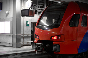 Red and blue passenger train at the platform of railway station. Commuter train is ready to departure from railway station