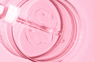 Petri dish. With transparent gel. The pipette lies. Cosmetic dispenser. On a pink background.