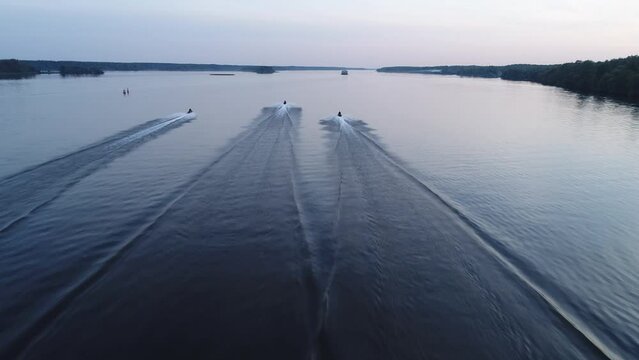 Aerial view. Three jet skis are moving fast along a wide river in a race. Riders on a water vacation compete with each other by driving an aquabike.