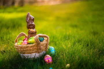 Easter eggs in basket with easter bunny on top. Chocolate rabbit with colorful decorated eggs in...