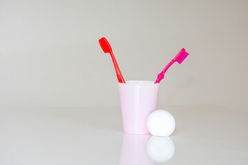 Bright colored toothbrushes in a cup and dental floss.