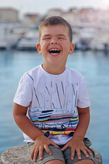 A portrait of a cute little boy who laughs on a warm summer day. Concept of summer holidays at sea and live style - 582286818