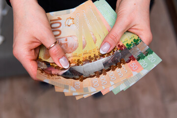 closeup on Canadian dollars in various denominations. A woman is counting Canadian money. Canadian...